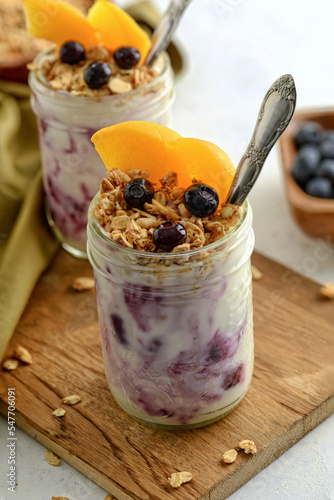 closeup of blueberry and peach granola parfait on wood cutting board