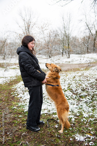 woman dancing with dog in winter park with snow
