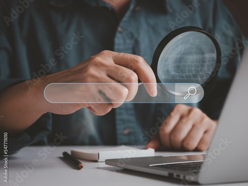 Man hold magnifying glass for searching information internet online, job searching in laptops. Virtual online search box browser.