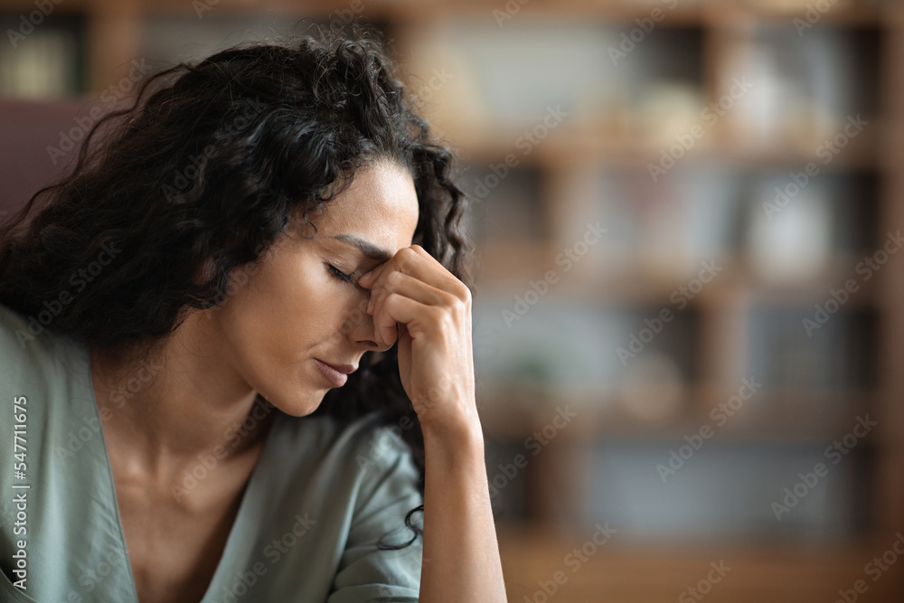 Upset brunette curly woman suffering from headache while working Upset brunette curly woman suffering from headache while working