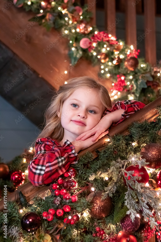 portrait of a little girl with long blond hair near a Christmas tree with garlands. Christmas concept