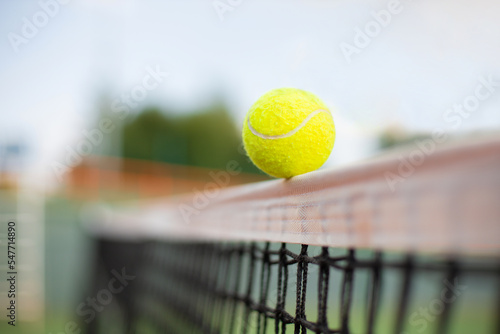 Bright greenish yellow tennis ball hitting the net. © ty
