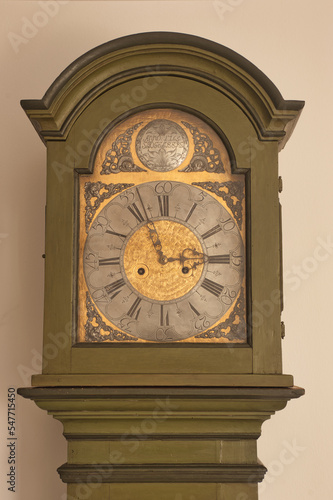Looking up at face of antique green grandfather clock on white background