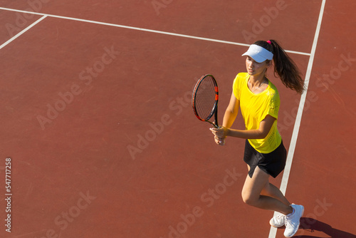 Professional equipped female tennis player beating hard the tennis ball with racquet. Top view. © ty