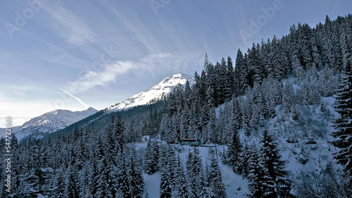 Ski slopes of the Austrian Alps. The sun illuminates the mountain tops with its morning rays. Mountain slopes with ski tracks on which skiers race. The road along the slopes of the mountain, in the mi