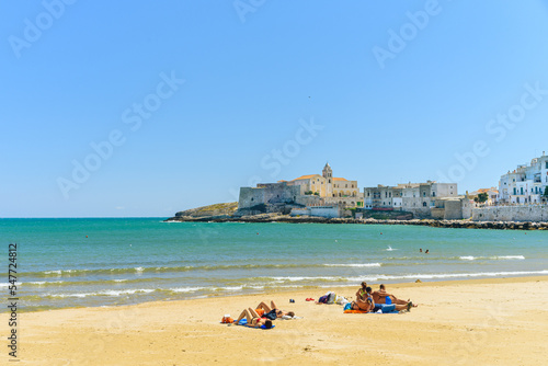 Fototapeta Naklejka Na Ścianę i Meble -  Vieste, Italy. View of the town with the beach of the Lungomare Cristoforo Colombo with some people. In the distance the Church of San Francesco. September 5, 2022.