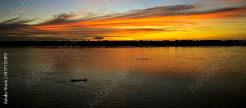 Sunset colors on the evening Mekong river. Juicy sunset on the Mekong River. Boat in the middle of the river in the beautiful colors of the setting sun. Mekong, Phnom Penh, Cambodia. 08/14/2006