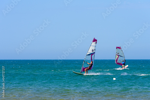 Vieste, Italy. In the sea of Vieste, near the Scialmarino beach, two people practice windsurfing. September 7, 2022 photo