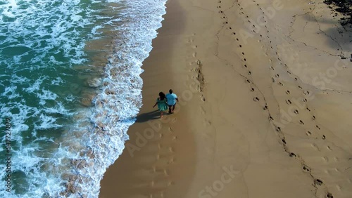 aerial drone footage of a black couple walking across the nice sandy beaches of Dominican Republic Punta Cana. the roman pair are on holiday enjoying a  relaxing tropical lifestyle.