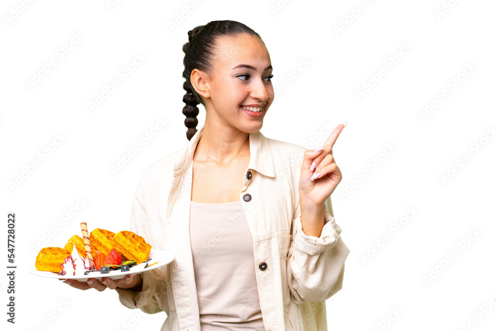 Young Arab woman holding waffles over isolated background intending to realizes the solution while lifting a finger up Young Arab woman holding waffles over isolated background intending to realizes the solution while lifting a finger up