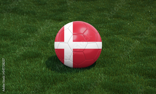 Soccer ball with Denmark flag colors at a stadium on green grasses background.