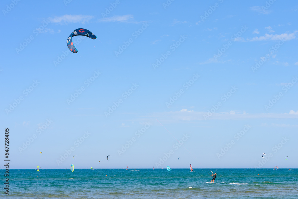 Vieste, Italy. In the sea of Scialmarino beach, a young man kitesurfing. In the background windsurfers and kitesurfers. September 7, 2022 Vieste, Italy. In the sea of Scialmarino beach, a young man kitesurfing. In the background windsurfers and kitesurfers. September 7, 2022