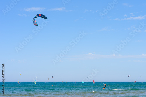 Vieste, Italy. In the sea of Scialmarino beach, a young man kitesurfing. In the background windsurfers and kitesurfers. September 7, 2022 photo