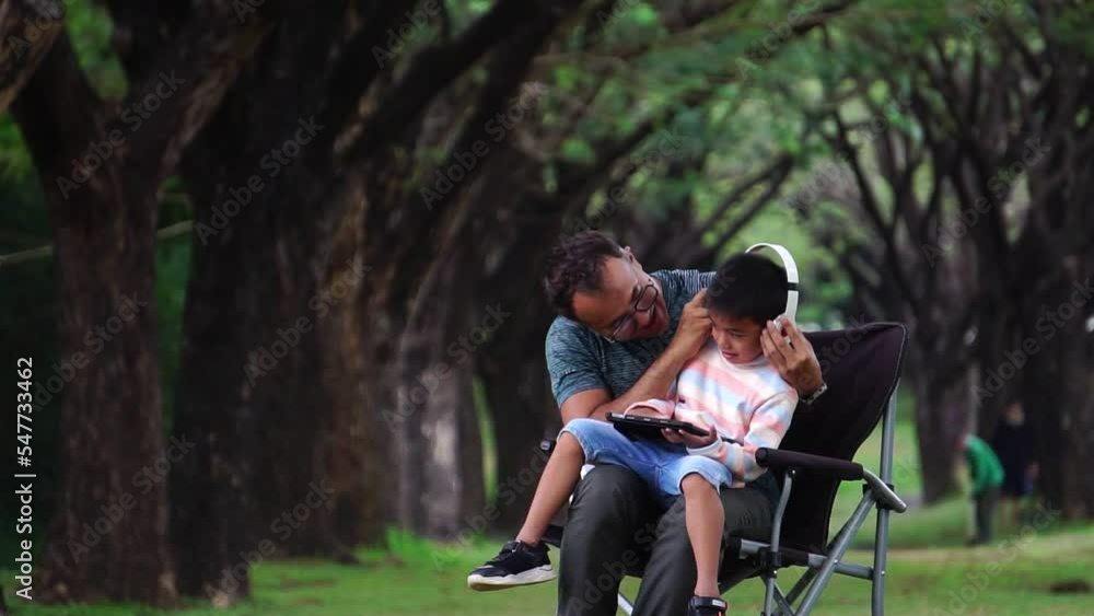 The children were happily sitting in the chairs with their father in the park The children were happily sitting in the chairs with their father in the park