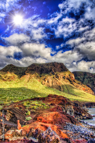 Clouds in blue sky and green fields with mountains on sunny day, north-west coast of Tenerife near Punto Teno Lighthouse, Canaria