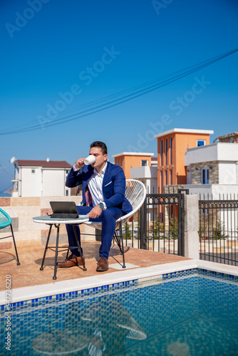 Adult businessman using laptop and phone