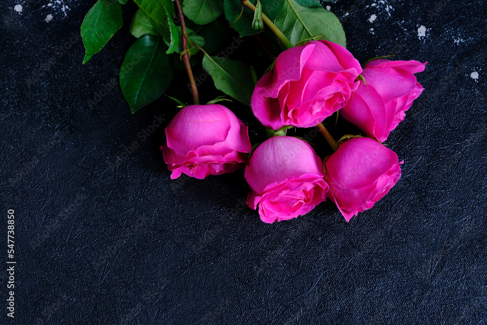 Fototapeta premium Pink roses, the bouquet is placed on a dark stone board. The scene depicts holiday greetings as well as love and romance.