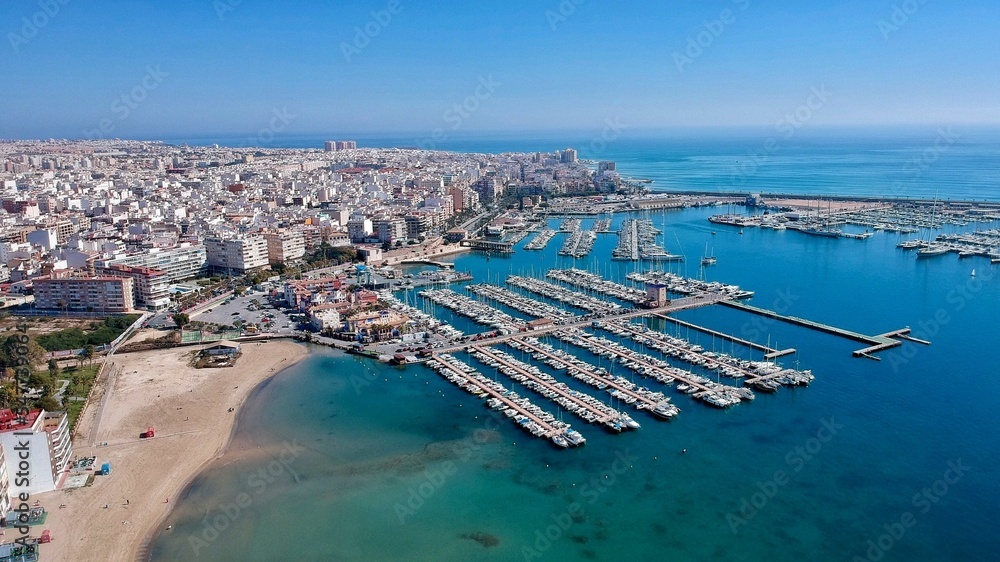 Naklejka premium Aerial shot of the Torrevieja Marina harbor with a cityscape in the background