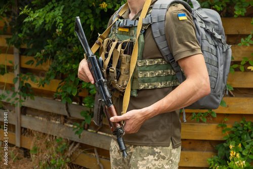 A military man in a military body armor with a tactical Kalashnikov automatic machine gun in his hands. Body armor with combat butts and ammunition. Аrmy. Military concept. No war.