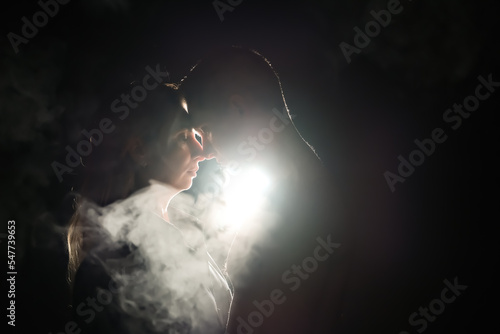 silhouette of a guy and a girl. men and women in the dark. smoke . steam . a man and a girl in a dark room are hugging. love concept.