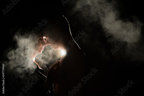 silhouette of a guy and a girl. men and women in the dark. smoke . steam . a man and a girl in a dark room are hugging. love concept.