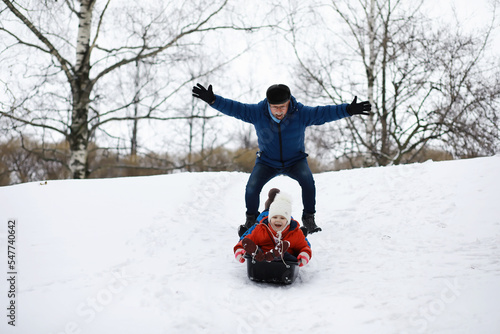 Children in the park in winter. Kids play with snow on the playground. They sculpt snowmen and slide down the hills.