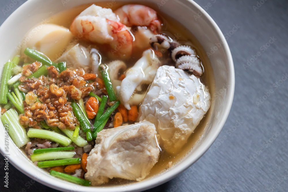 Bowl of rice porridge with sea bass fish, shrimp, squid, pork  and egg tofu. Top view with copy space.