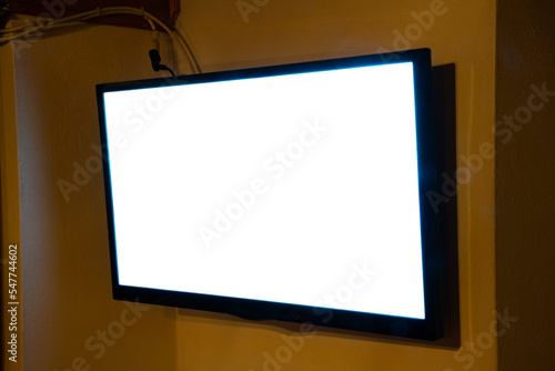 A flat TV set mounted on the wall of a room. Angled shot, blank cutout screen. 