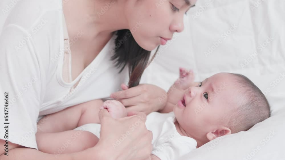 Happy family, Cute Asian newborn baby boy playing with mom takes care nearby on white bed with smile happy face. Little innocent new infant adorable child in first day of life. Mother's Day concept. Happy family, Cute Asian newborn baby boy playing with mom takes care nearby on white bed with smile happy face. Little innocent new infant adorable child in first day of life. Mother's Day concept.