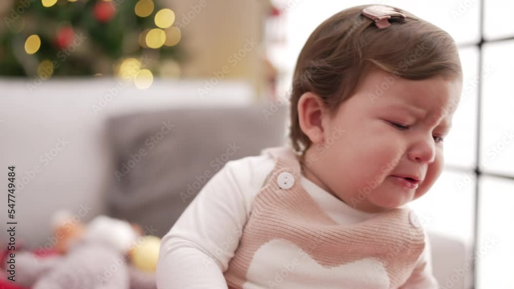 Adorable toddler standing by christmas tree crying at home Adorable toddler standing by christmas tree crying at home