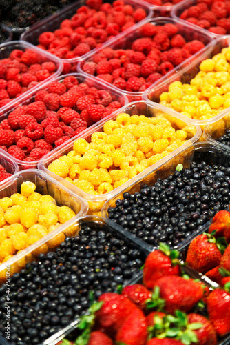 Colourful mix of different fresh berries at market. Raspberries, strawberries and bilberries.