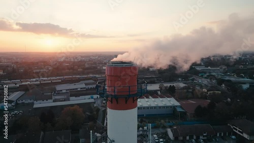 Aerial drone footage of an Industrial Chimney, smoke emission, flying near the pollutant in the air, burning gas for heat
