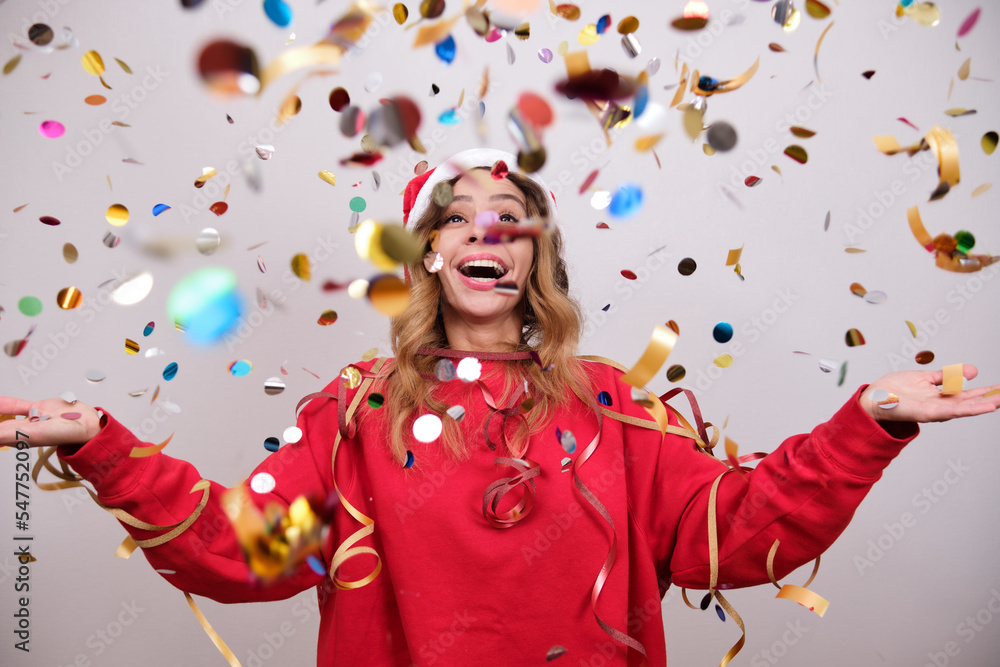 Fototapeta premium Woman in a New Year's hat is happy with confetti.