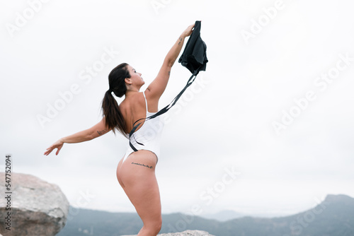 Fotografi Caucasian mature woman scantily clad a black skirt in hand and arms outstretched