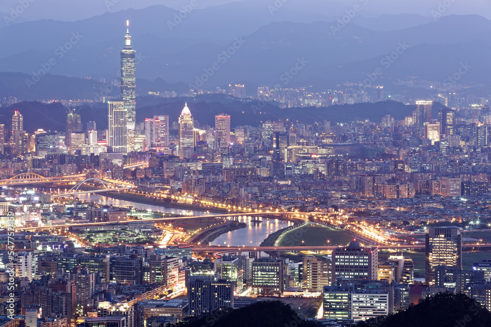 Aerial panorama of Taipei downtown and suburbs at dusk with view of Keelung Riverside Park, MacArthur bridge and 101 Tower in Xinyi District. A romantic night in busy Taipei City in a gloomy blue mood