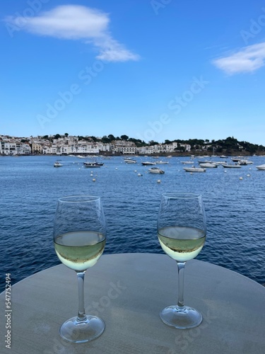 Copas de vino blanco con vistas espectaculares a la costa y al puerto pesquero de Cadaqués en la Costa Brava. 