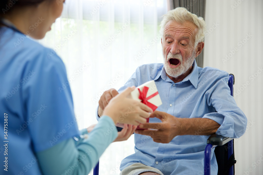 senior man taking a gift box from caregiver for happy birthday senior man taking a gift box from caregiver for happy birthday