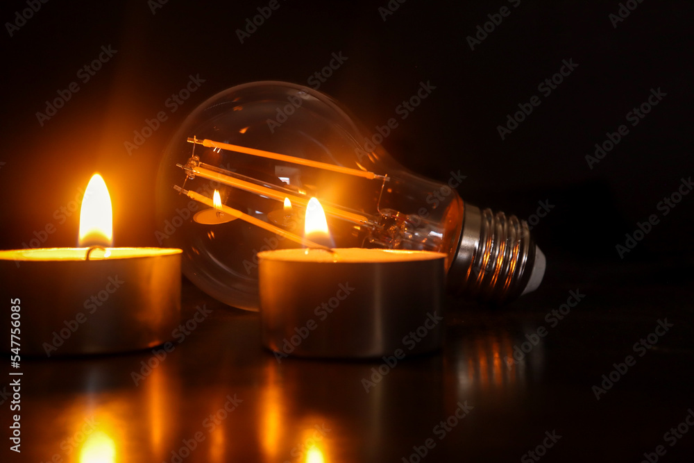 Lightbulb with candles in the background. Concept of loadshedding