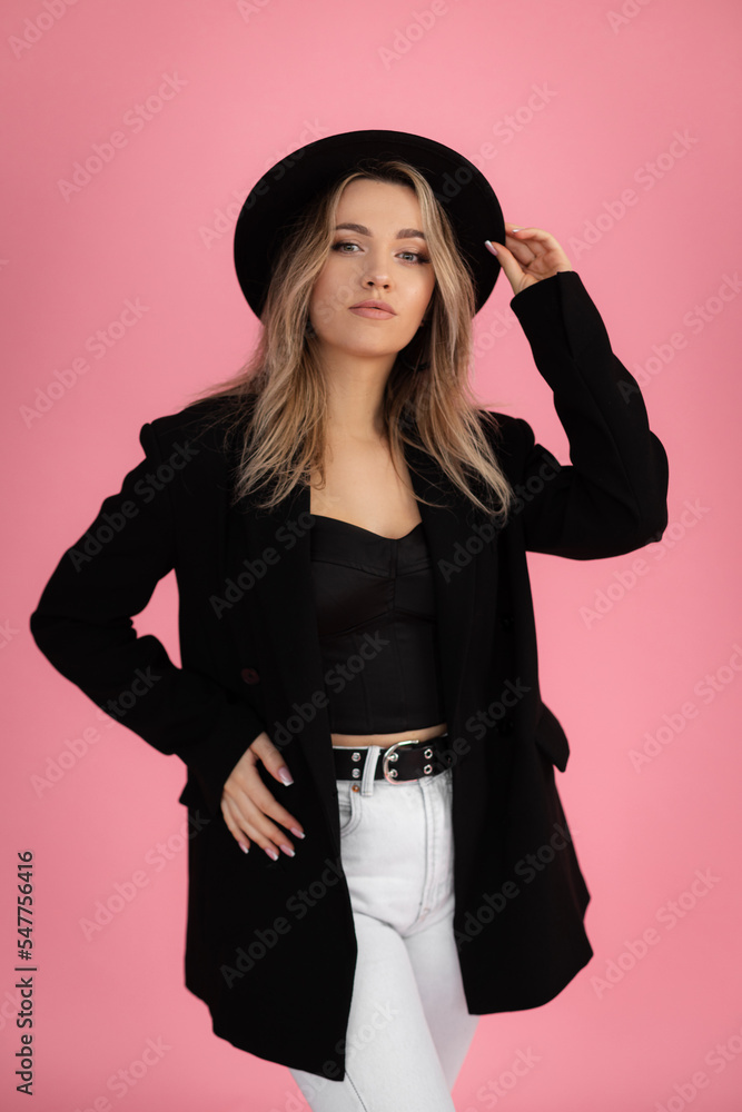 Vertical cool, confident, pretty blond woman in hat posing and look camera with hands on hips, on hat in black outfit Vertical cool, confident, pretty blond woman in hat posing and look camera with hands on hips, on hat in black outfit