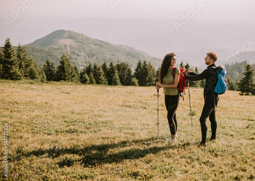 Smiling couple preparing hiking adventure with backpacks by terrain vehicle