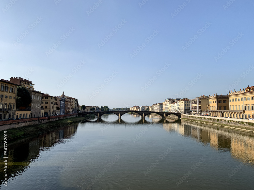 Fototapeta premium Firenze, Tuscany, Italy. Sunny day at Arno River, the Lungarno and the Ponte alla Carraia bridge, in a view from the Santa Trinità bridge. The neighborhood surrounding the Arno river
