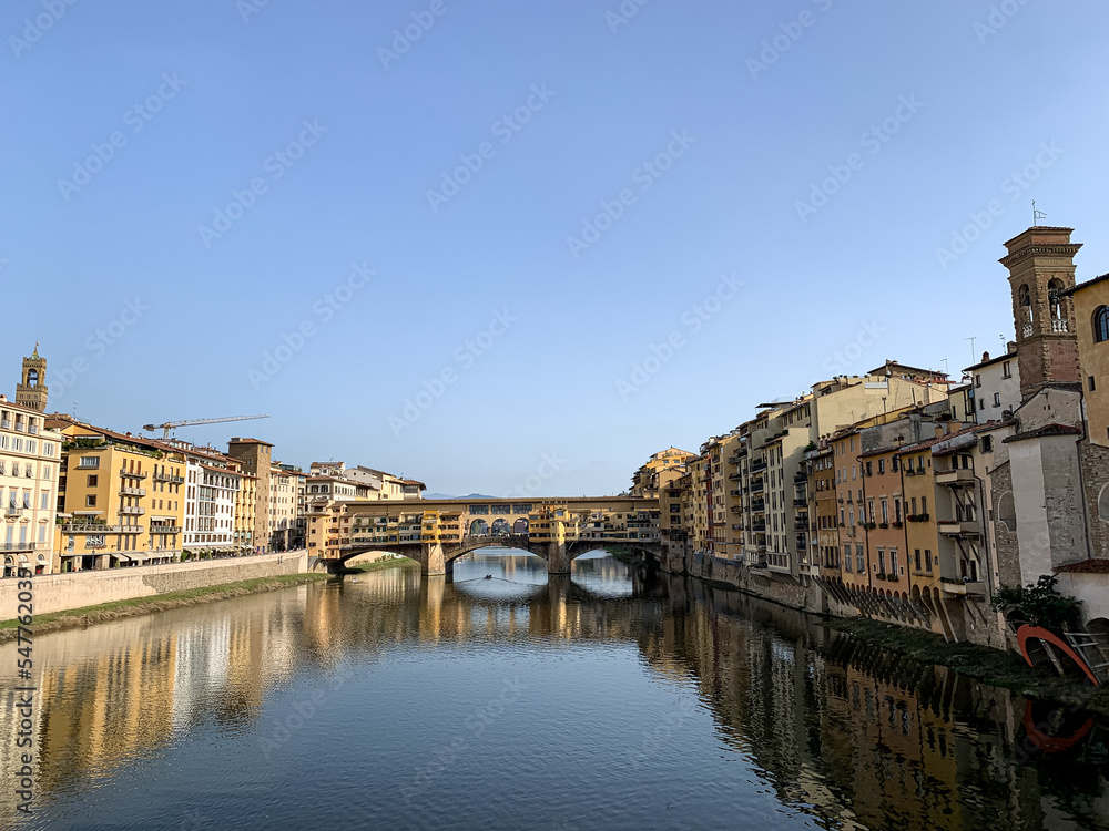 Firenze, Tuscany, Italy - 18.10.2022. Ponte Vecchio Bridge during beautiful sunny day with reflection in Arno River, Florence, Italy. Picturesque medieval arched river bridge with Roman origins, lined