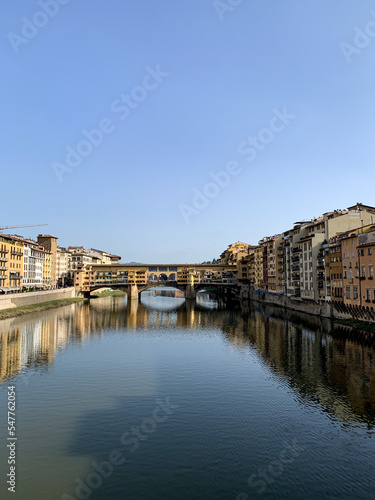 Firenze  Tuscany  Italy. Ponte Vecchio Bridge during beautiful sunny day with reflection in Arno River  Florence  Italy. Picturesque medieval arched river bridge with Roman origins  lined
