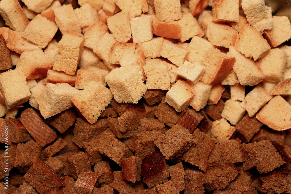 a lot of ruddy fried square croutons of white and black bread randomly scattered in a pile - close-up top view a lot of ruddy fried square croutons of white and black bread randomly scattered in a pile - close-up top view