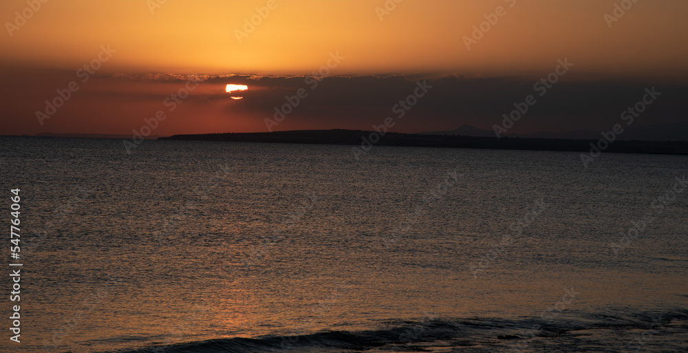Sunrise in the sea with cloud stormy clouds and orange colour. Seascape at sunset. Sun rays in the ocean