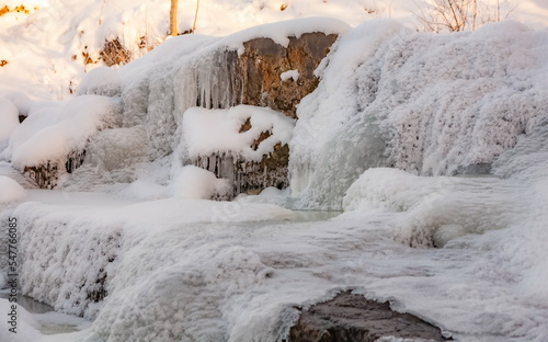Frozen river flowing over rocks, ice and snow in winter © Александр Коликов