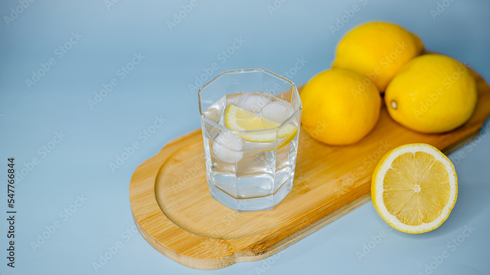 yellow lemons lie on a wooden board with a glass of water on a blue background yellow lemons lie on a wooden board with a glass of water on a blue background