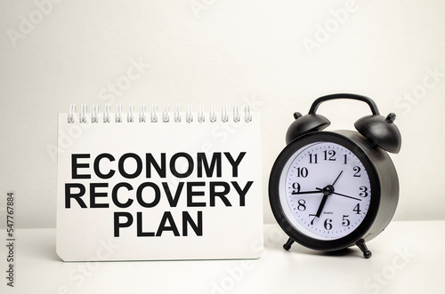 ECONOMY RECOVERY PLAN words with calculator and clock with notebook