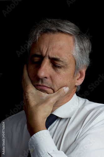 headache. concern. concentration. portrait. dark key. Man with gray hair, tie and white shirt.