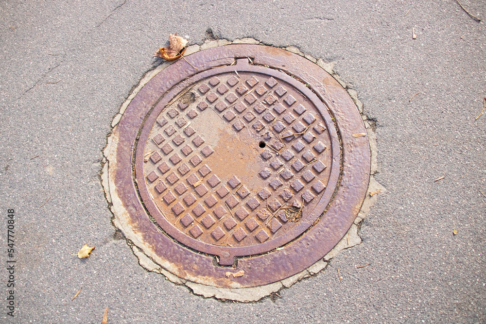 Sewer manhole with lid on the sidewalk